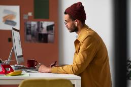 un graphic designer seduto alla scrivania mentre lavora al computer sulla scelta del font migliore