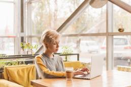 ragazza seduta in un bar mentre lavora al computer