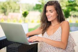 una ragazza mentre scrive sul suo portatile seduta in un parco