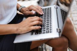 una ragazza seduta mentre scrive sul suo portatile