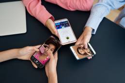 tre ragazze mentre condividono i contenuti dei vari social sui loro iPhone