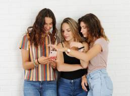 tre ragazze mentre commentano l'articolo che stanno leggendo sul loro iPhone
