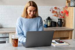 una ragazza seduta al bancone della cucina mentre lavora al computer