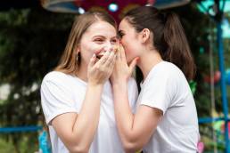 due ragazze mentre sussurrano all'orecchio news sul loro brand preferito