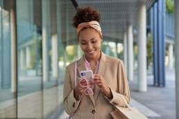 una ragazza mentre passeggia leggendo le digital news di ottobre sul suo iPhone