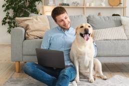 ragazzo in compagnia del suo cane legge le digital news di ottobre sul sul Mac