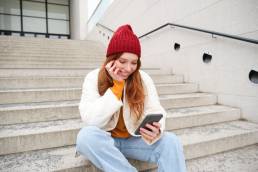 ragazza seduta sulle scale mentre guarda contenuti social sul suo iPhone