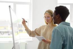 Due colleghi che collaborano davanti a una lavagna bianca