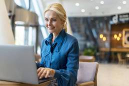Donna in camicia blu che lavora su un laptop