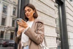 Donna elegante per strada che guarda il suo smartphone