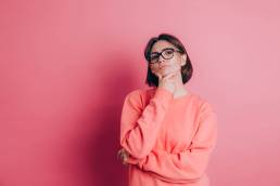 ragazza pensierosa con maglione rosa su sfondo rosa