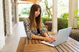 una donna mentre lavora al suo portatile seduta su una terrazza