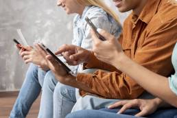 un gruppo di amici seduti insieme mentre guardano tablet e iPhone