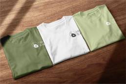 Tre magliette piegate verde, bianca e verde chiaro con logo &ldquo;Il Rifugio di Anna&rdquo;.