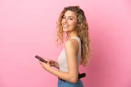 ragazza riccia bionda mentre manda un messaggio con il suo iPhone